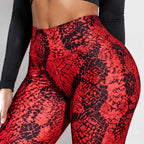 Red and black snakeskin print high-waisted leggings worn by a model, shown from the waist down against a light gray background.