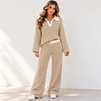 A woman front viewed wearing a matching khaki and white horizontally striped two-piece lounge set, walking outdoors against a white wall.
