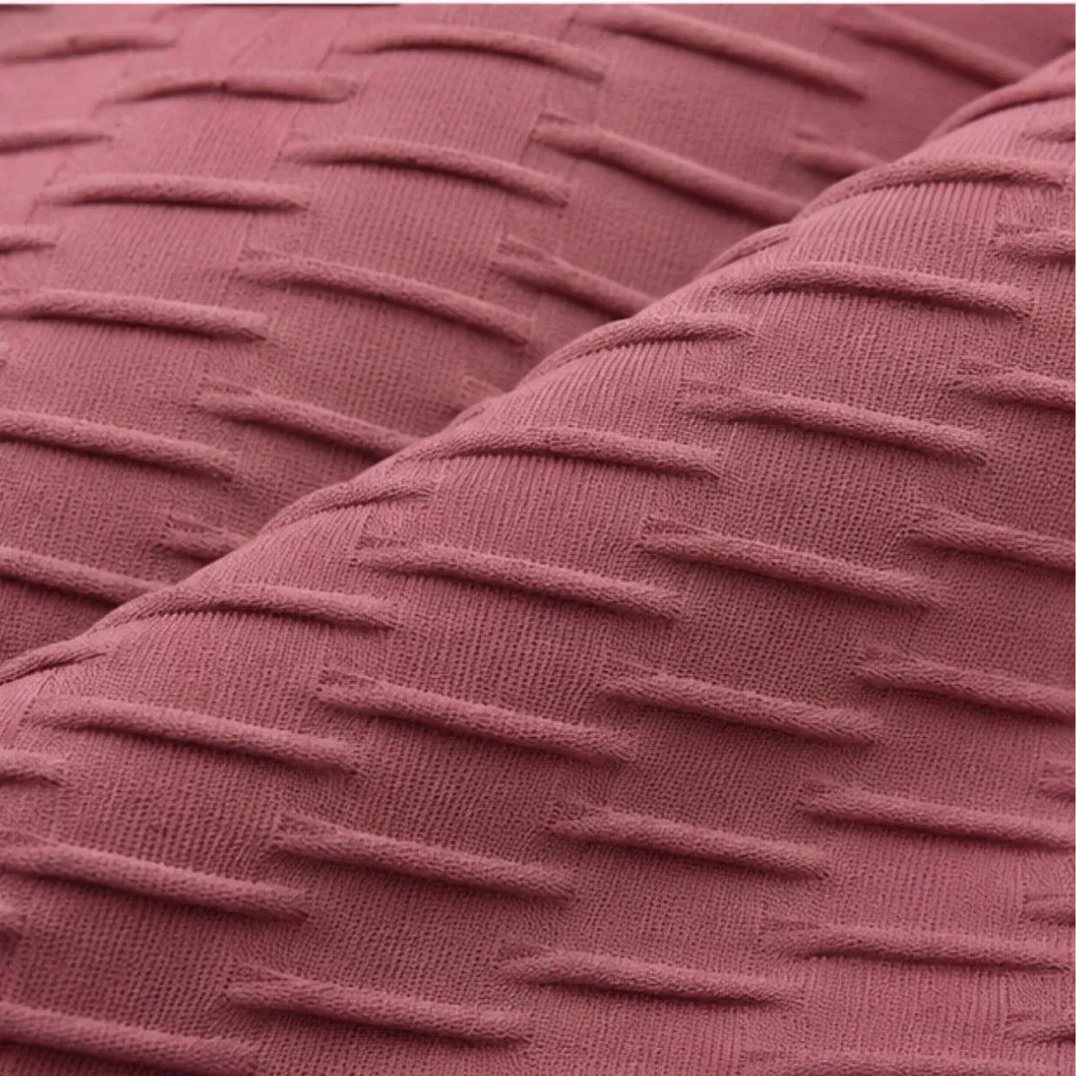 A close-up of a textured fabric with a dusty rose or mauve color and a raised horizontal stripe pattern.