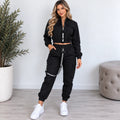Women’s black utility jogger two-piece set with cropped zip jacket, cargo pockets, elastic jogger cuffs, and black strap details.