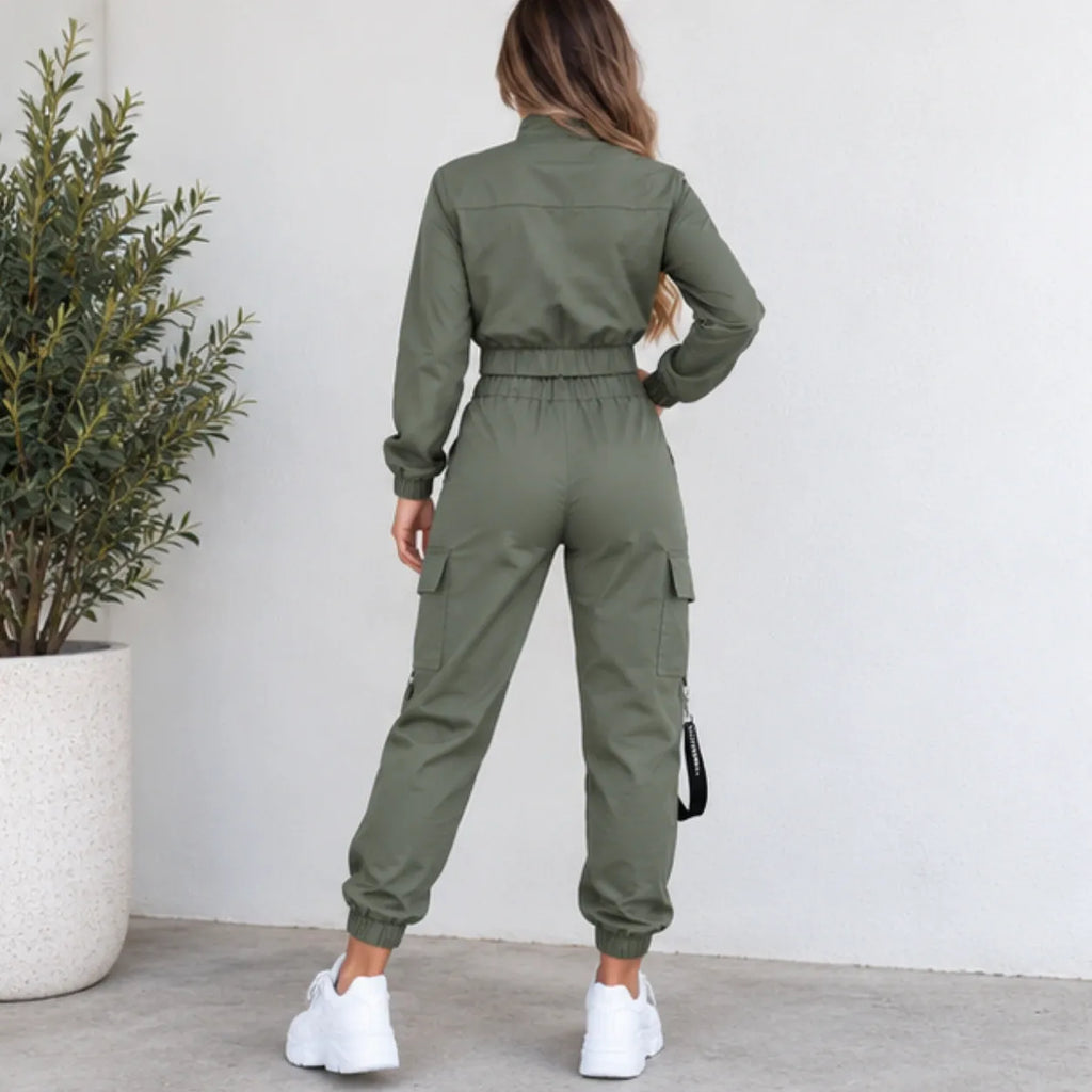 Back view of women’s olive green utility jogger two-piece set showing the cropped jacket, elastic waistband, cargo pockets, and black side strap detail.