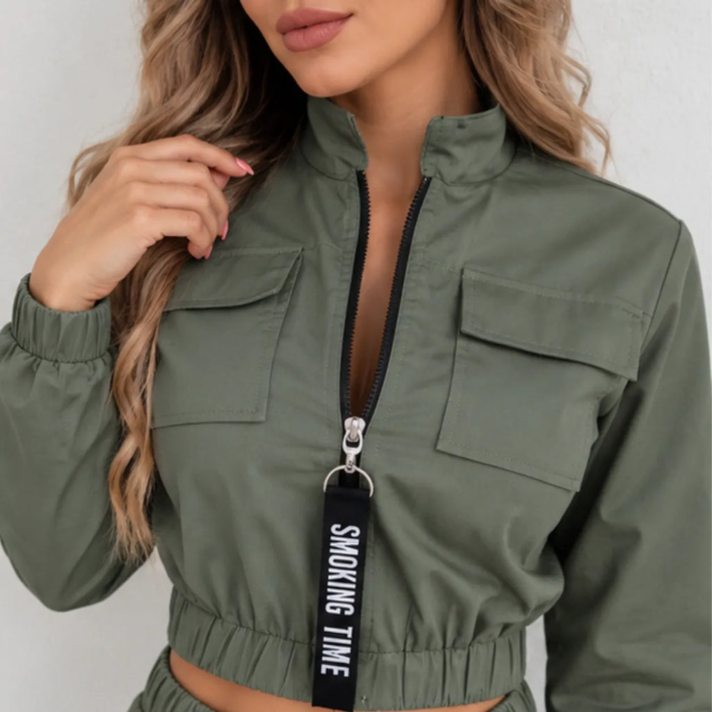 Close-up of women’s olive green utility jogger jacket featuring a front zipper, flap chest pockets, elastic waistband, and black zipper pull detail.