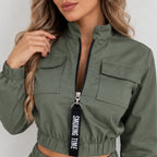 Close-up of women’s olive green utility jogger jacket featuring a front zipper, flap chest pockets, elastic waistband, and black zipper pull detail.