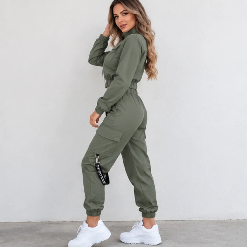 Women’s olive green utility jogger two-piece set shown from the side, featuring a cropped zip jacket, cargo jogger pants, and black strap detail.