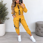 Women’s yellow utility jogger two-piece set with cropped zip jacket, cargo pockets, adjustable black strap details, and white sneakers.