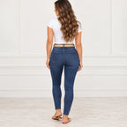 Apricot, back: Rear view of an apricot woven elastic belt threaded through the waistband of blue jeans.