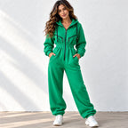 A woman modeling a bright green zip-up hoodie sweatshirt and matching jogger pants set, standing against a white textured wall.