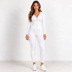 A woman modeling a white long-sleeve zip-up hoodie and matching white leggings, paired with white sneakers, against a plain white studio background.