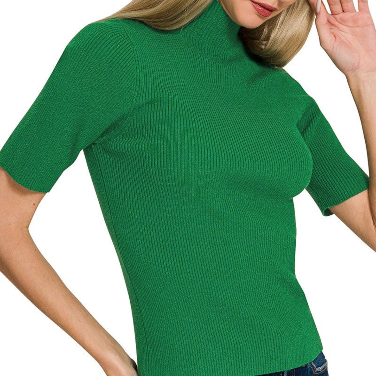 Woman wearing a green ribbed sweater and blue jeans on a white background