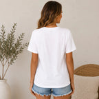 Back view of a women's white crewneck graphic T-shirt with patriotic America cherry bow design, styled with distressed denim shorts.