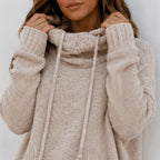 Close-up of apricot oversized knit cowl neck pullover showing textured knit fabric, cowl neckline and drawstrings