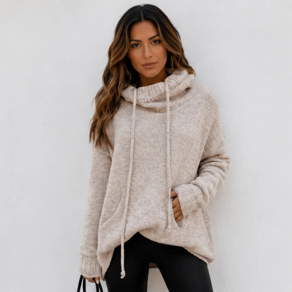 Woman wearing an apricot oversized knit cowl neck pullover with long sleeves and drawstring neckline