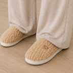 Women's Aspen Cozy Knit House Slippers in light brown featuring a cozy knit upper, embroidered bear detail, and non-slip sole.