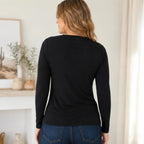 Back view of a women's black asymmetrical long sleeve top with a clean minimalist design and fitted silhouette, paired with dark wash jeans.