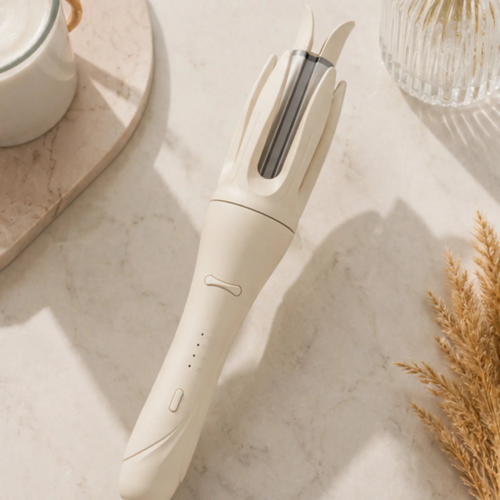Ivory automatic rotating curling iron displayed on a marble vanity with beauty accessories.