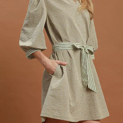Model wearing a flattering Umgee textured tie waist dress from Solazura Boutique