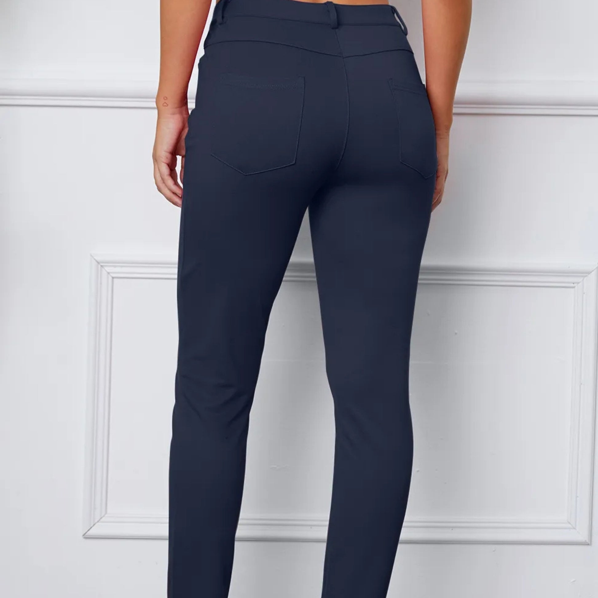 Navy blue pants worn by a person on a white paneled wall background