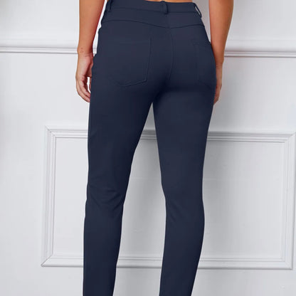 Navy blue pants worn by a person on a white paneled wall background