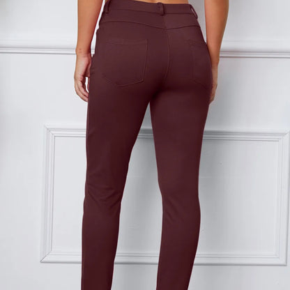 Maroon pants worn by a person against a white paneled wall