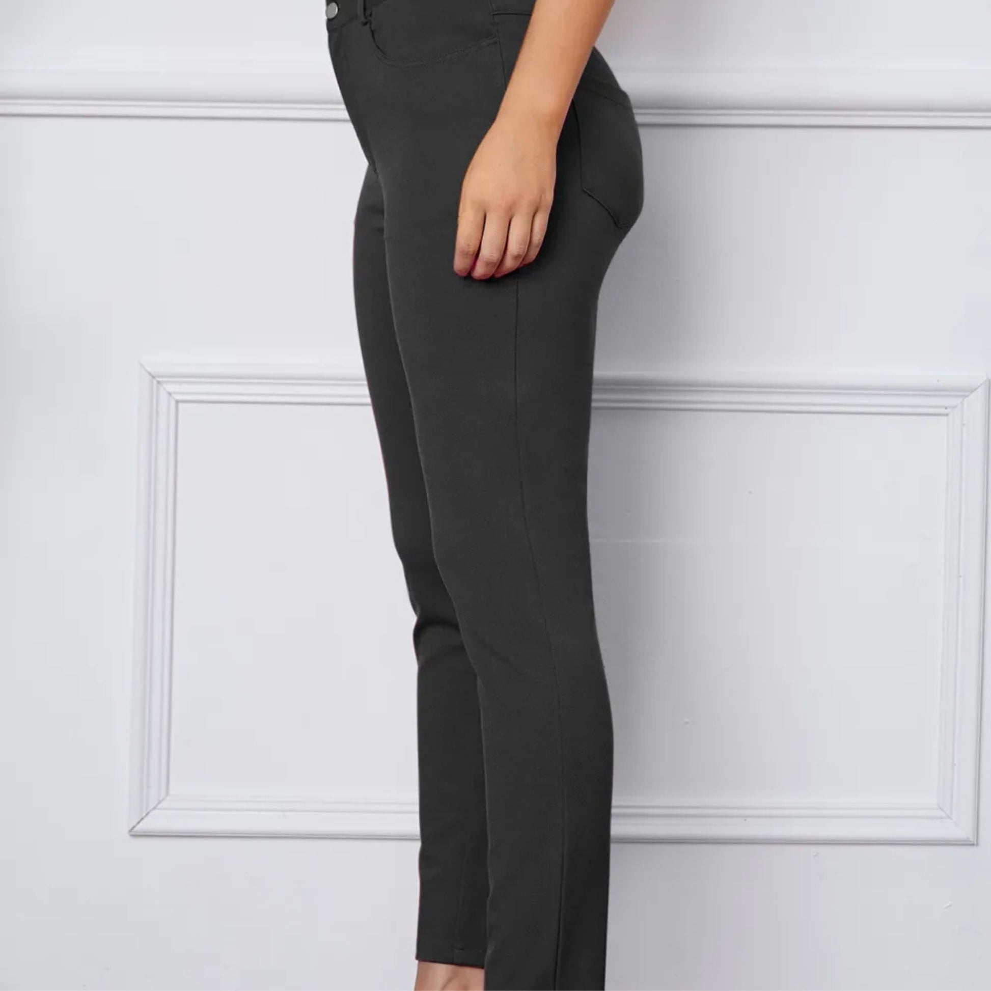 Dark grey pants worn by a person on a white background