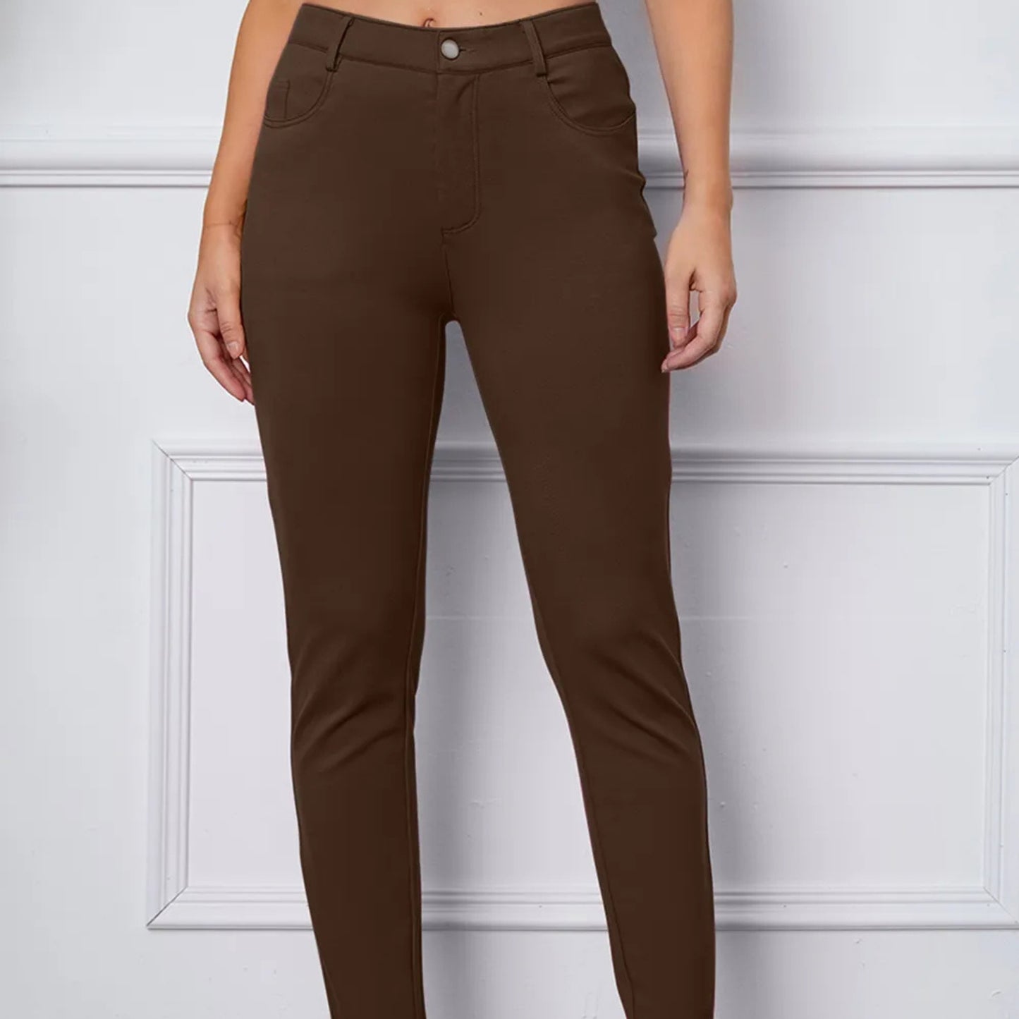 Brown pants worn by a person against a white wall