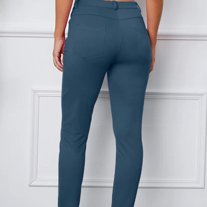 Teal pants worn by a person against a white paneled wall