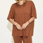 Women's rust brown oversized lounge set featuring a relaxed V-neck short sleeve top with matching biker shorts.