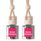 Two Berry Mimosa reed diffusers with clear glass bottles, pink labels, beige wooden stoppers, and natural fiber hanging cords on a white background.