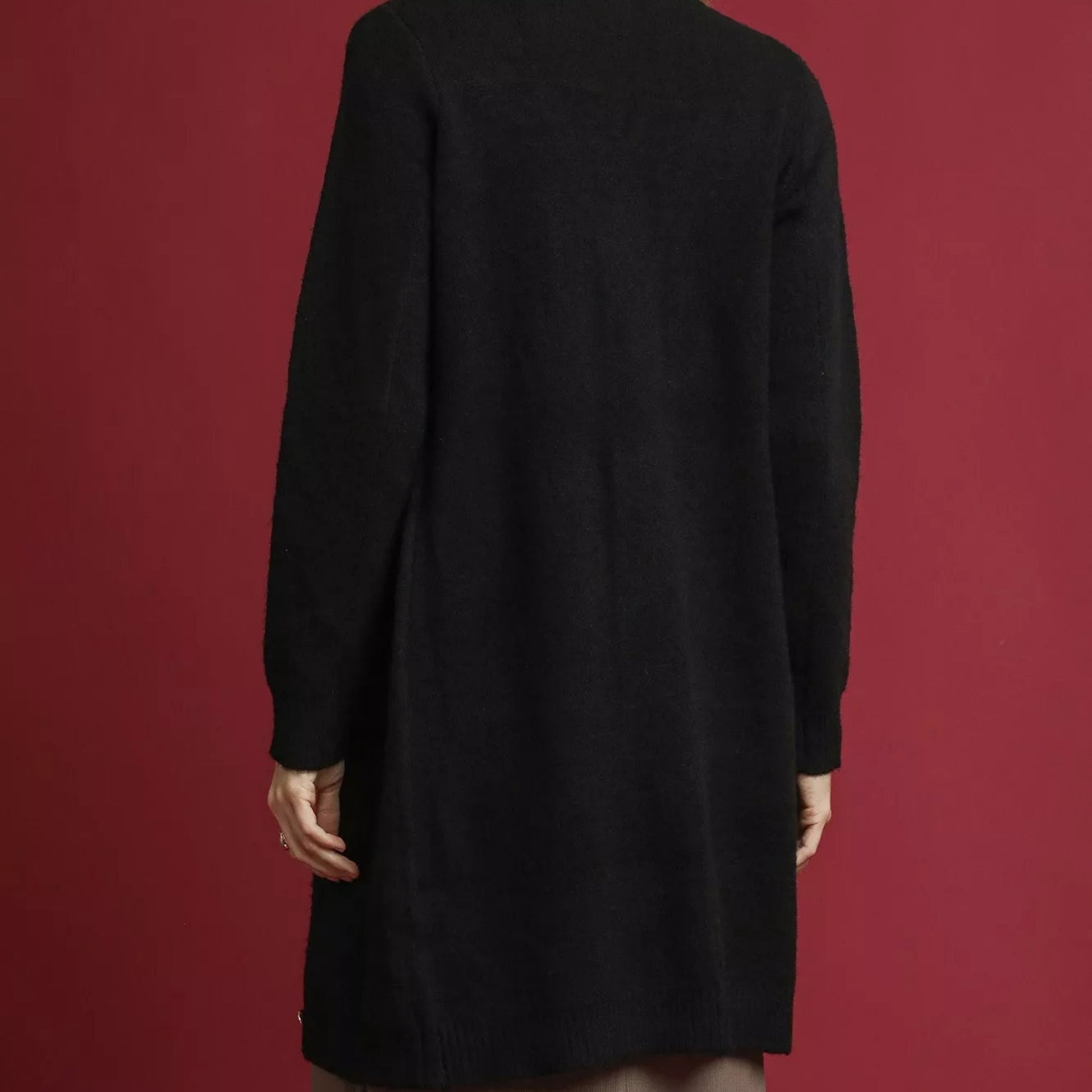 Black coat worn by a person on a red background