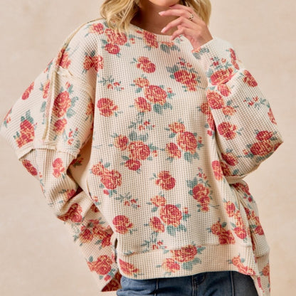 Floral patterned sweater worn by a person on a beige background