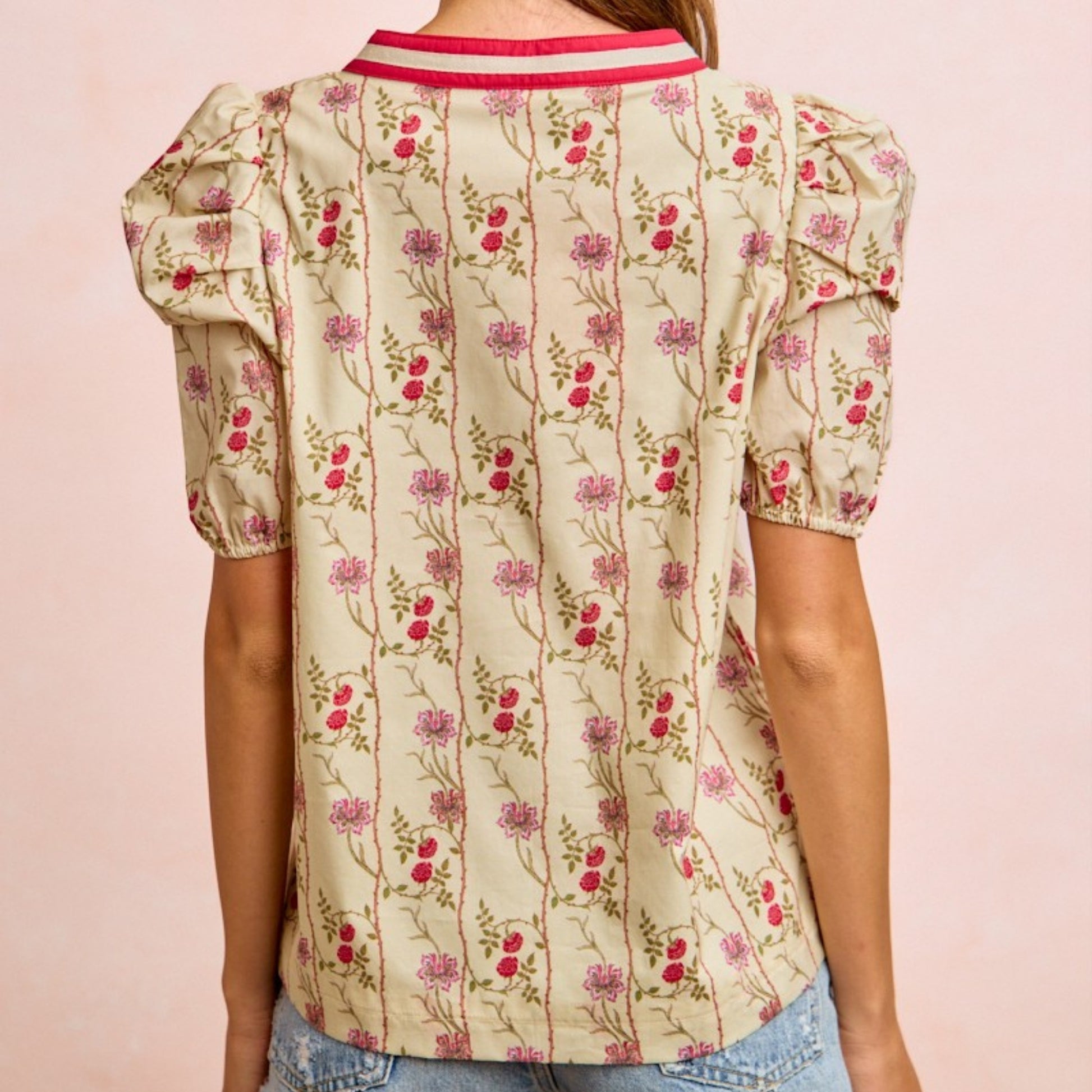 Floral patterned blouse with puff sleeves on a pink background