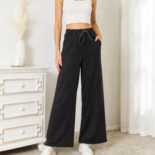 Woman wearing black drawstring wide leg lounge pants with pockets and a relaxed fit.