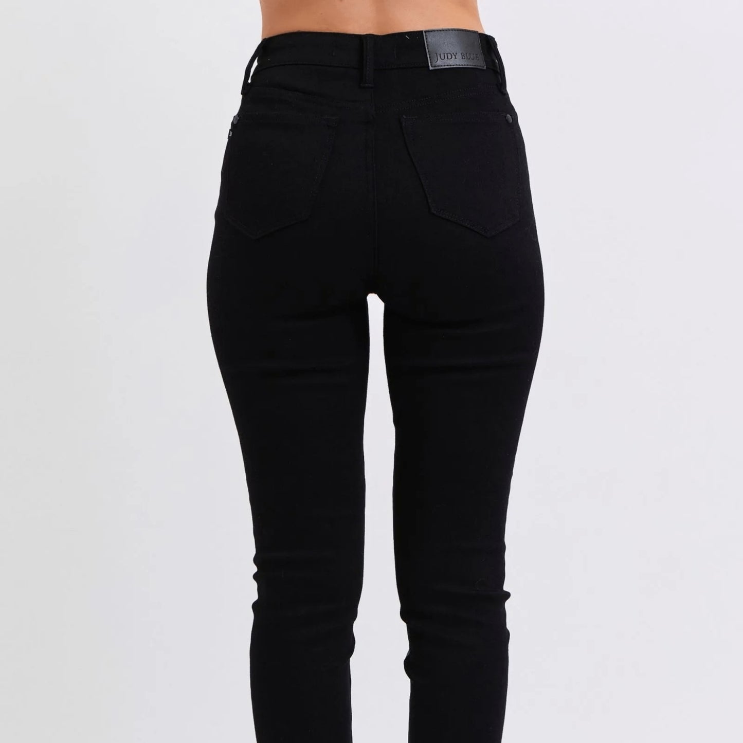 Lifestyle shot of black faux leather skinny pants styled for a fashion-forward look.