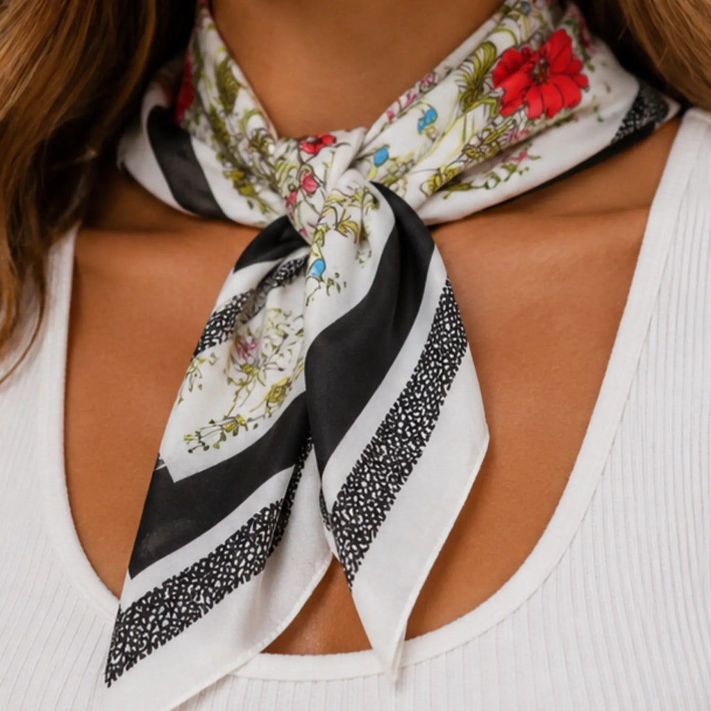 Close-up of a black floral multi print square scarf highlighting the colorful floral design, black border, and lightweight fabric.