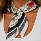 Close-up of a black floral multi print square scarf highlighting the colorful floral design, black border, and lightweight fabric.