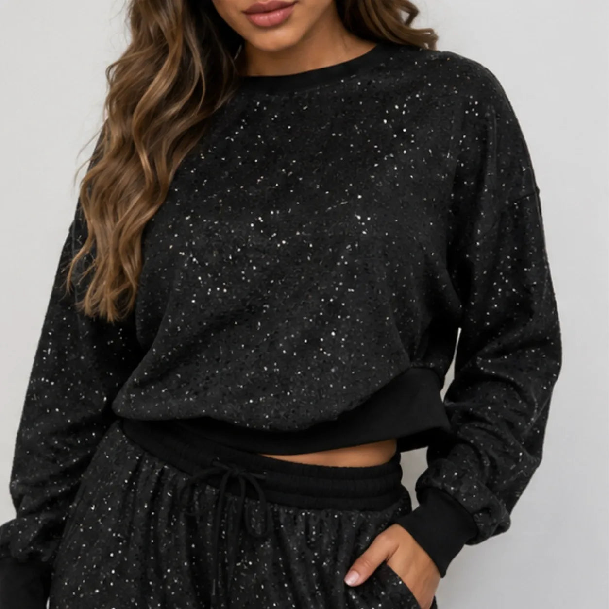 Close-up of black sequin sweatshirt and drawstring wide-leg pants set showing sequin detail and ribbed waistband