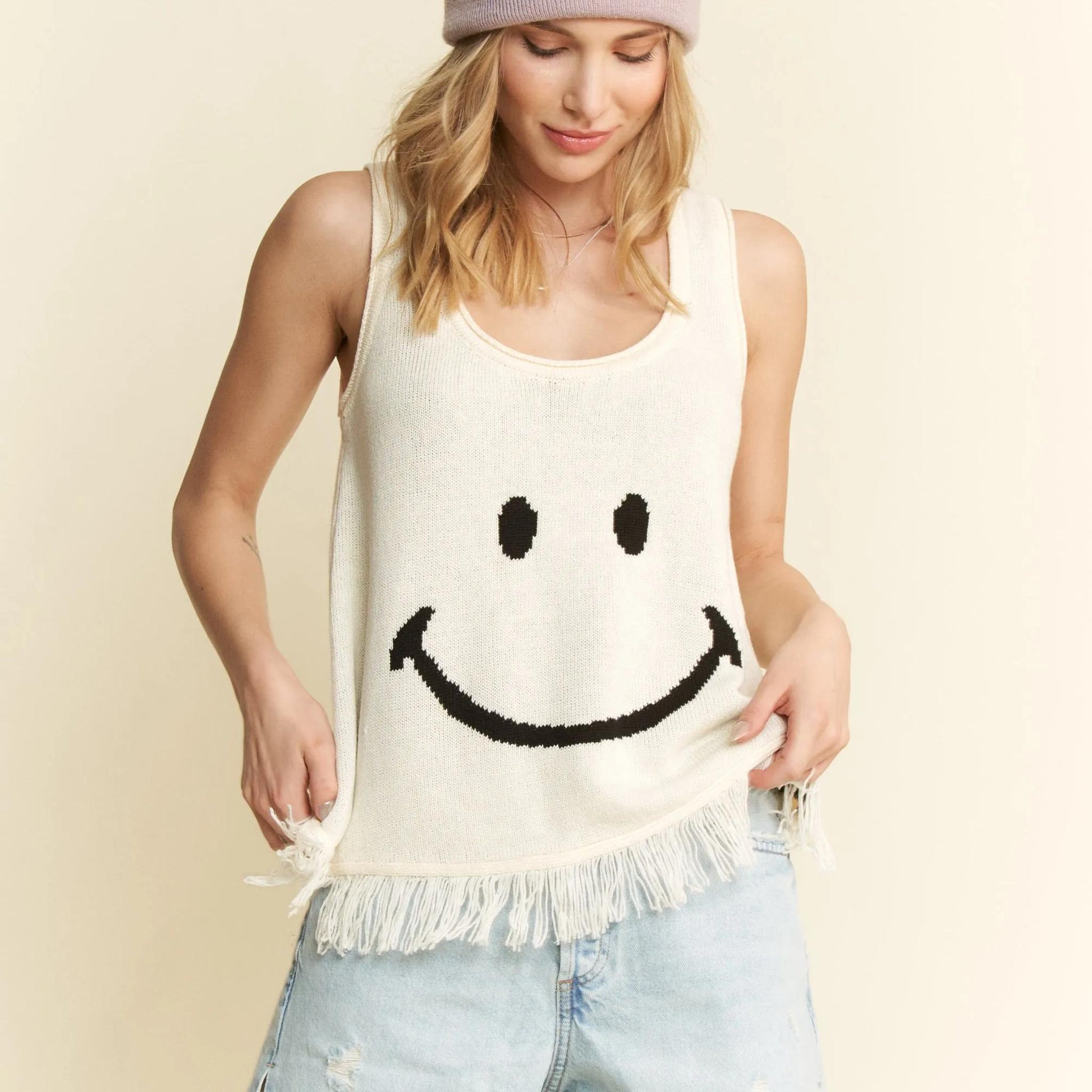 Close-up of the black smiley face graphic and decorative fringe hem.