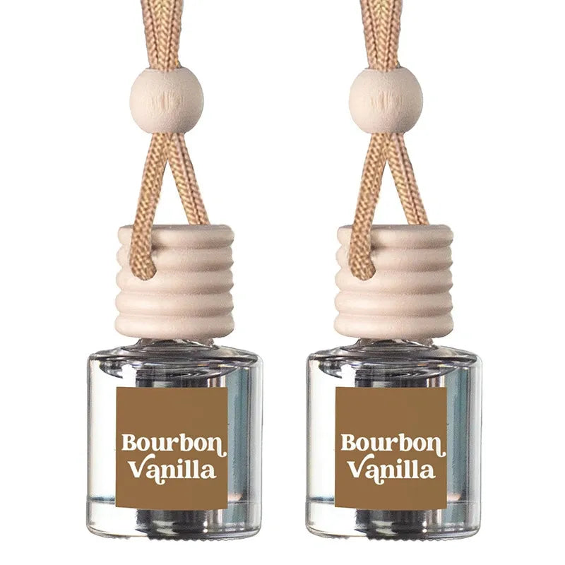 Two reed diffuser bottles with clear glass bodies, beige wooden caps, and tan hanging cords, each labeled Bourbon Vanilla on a white background.