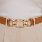 Close-up of a camel elastic waist belt featuring a textured gold chain buckle.