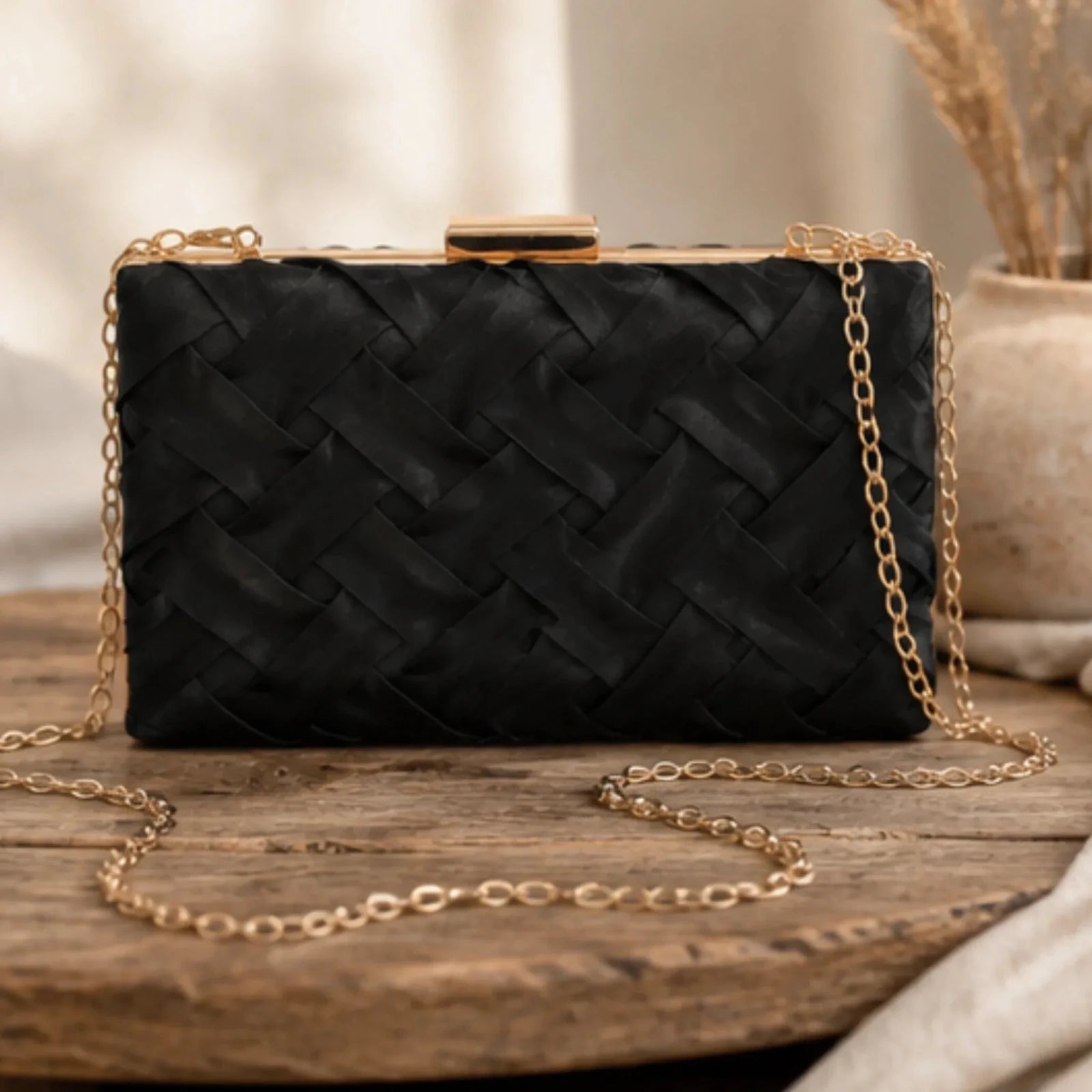 Crosshatch Chain Clutch Bag in black displayed with its woven satin exterior, structured silhouette, gold-tone hardware, and removable chain strap.