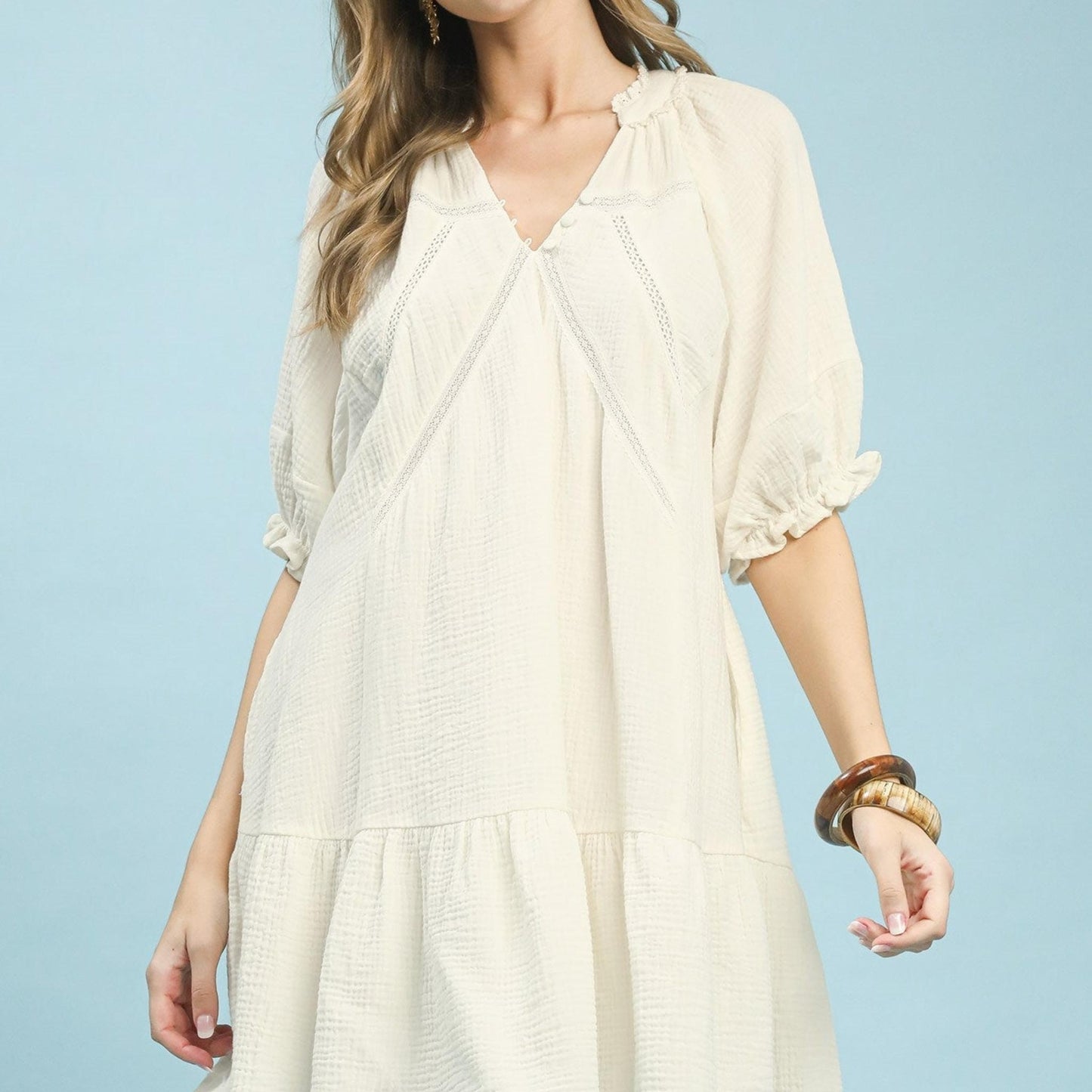 Woman wearing a light beige dress against a light blue background
