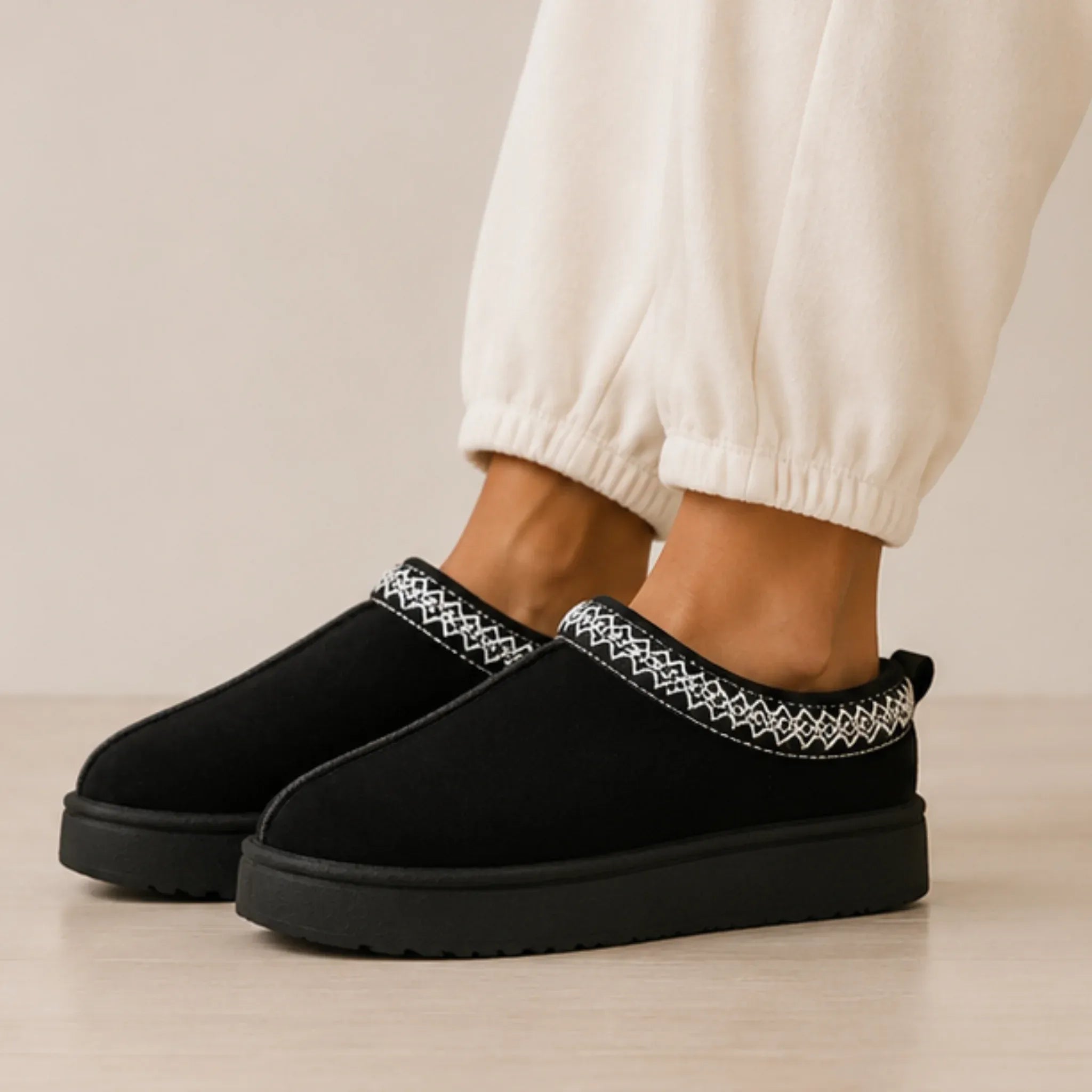 Angled view of black Cozy Fleece-Lined House Slippers with a cozy fleece lining, slip-on design, and supportive platform sole.