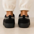 Rear view of black Cozy Fleece-Lined House Slippers showing the pull tab, embroidered collar trim, and durable platform sole.