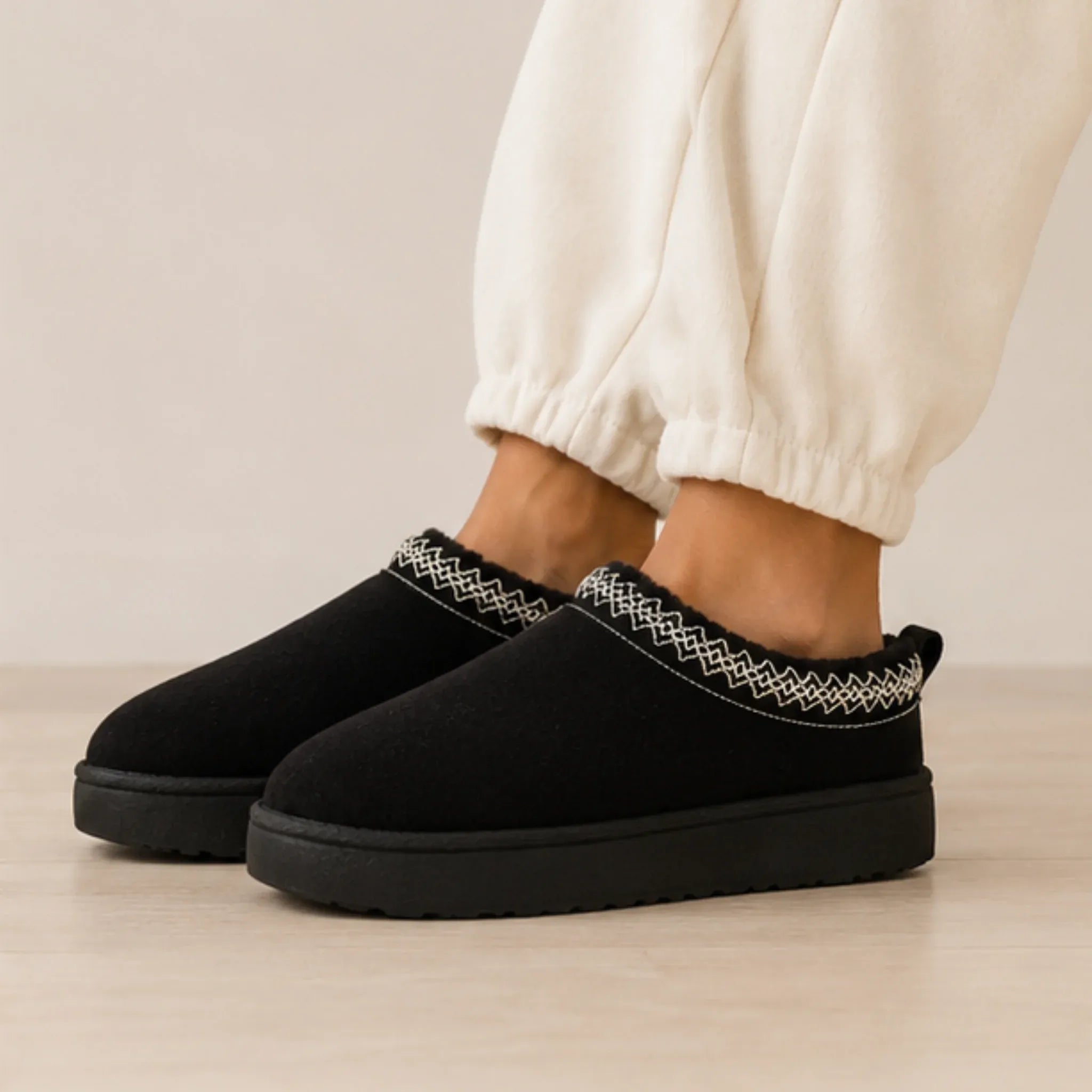 Black Cozy Fleece-Lined House Slippers featuring a soft suede upper, embroidered trim, plush fleece lining, and lightweight platform sole.