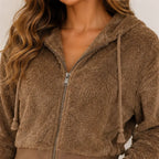 Close-up of women's brown plush zip-up hoodie showing zipper, hood, and drawstring details