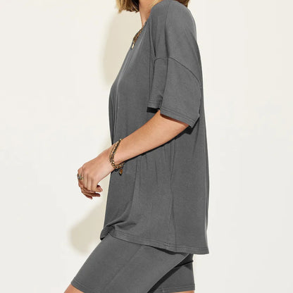 Person wearing a gray oversized t-shirt on a plain background