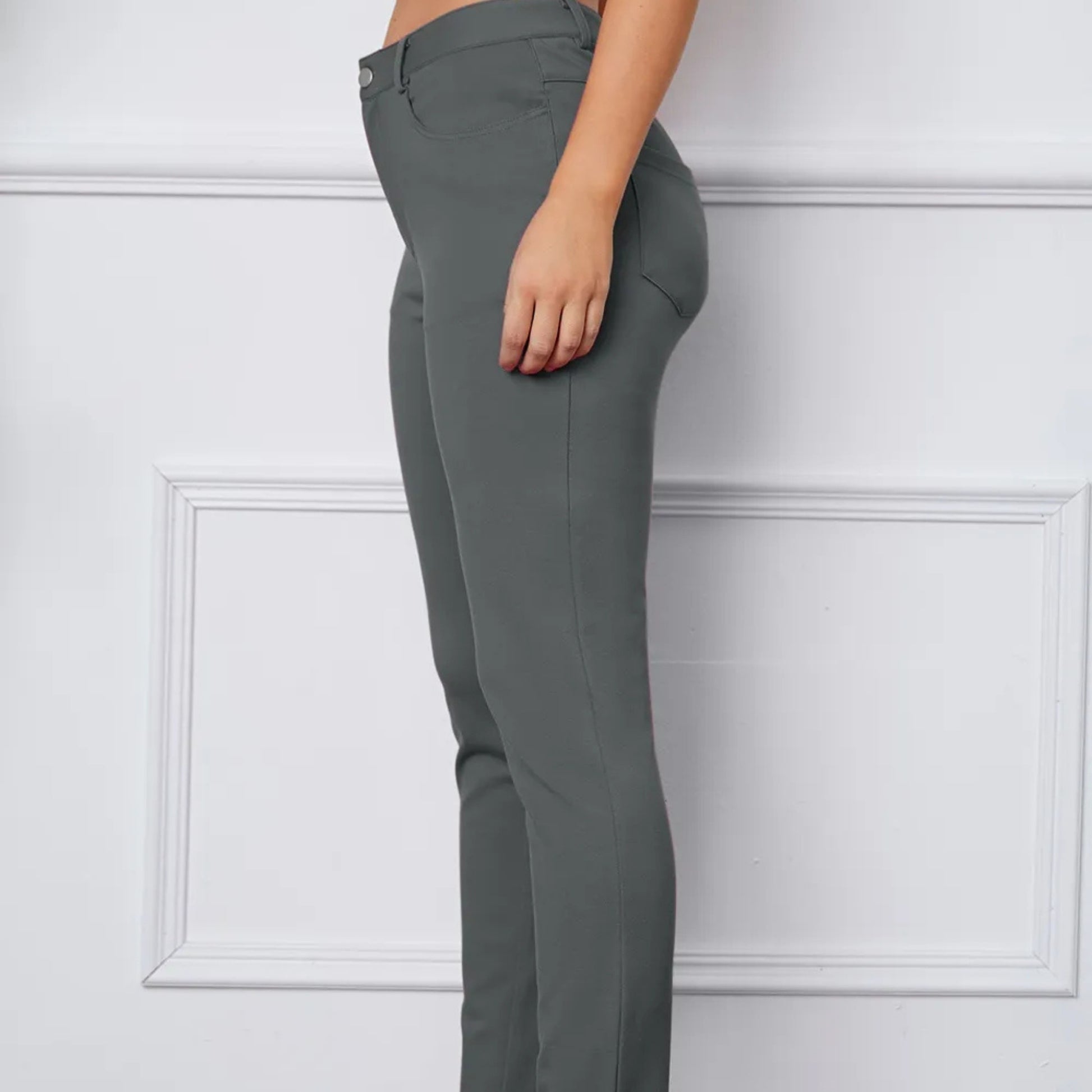 Gray pants worn by a person against a white paneled wall