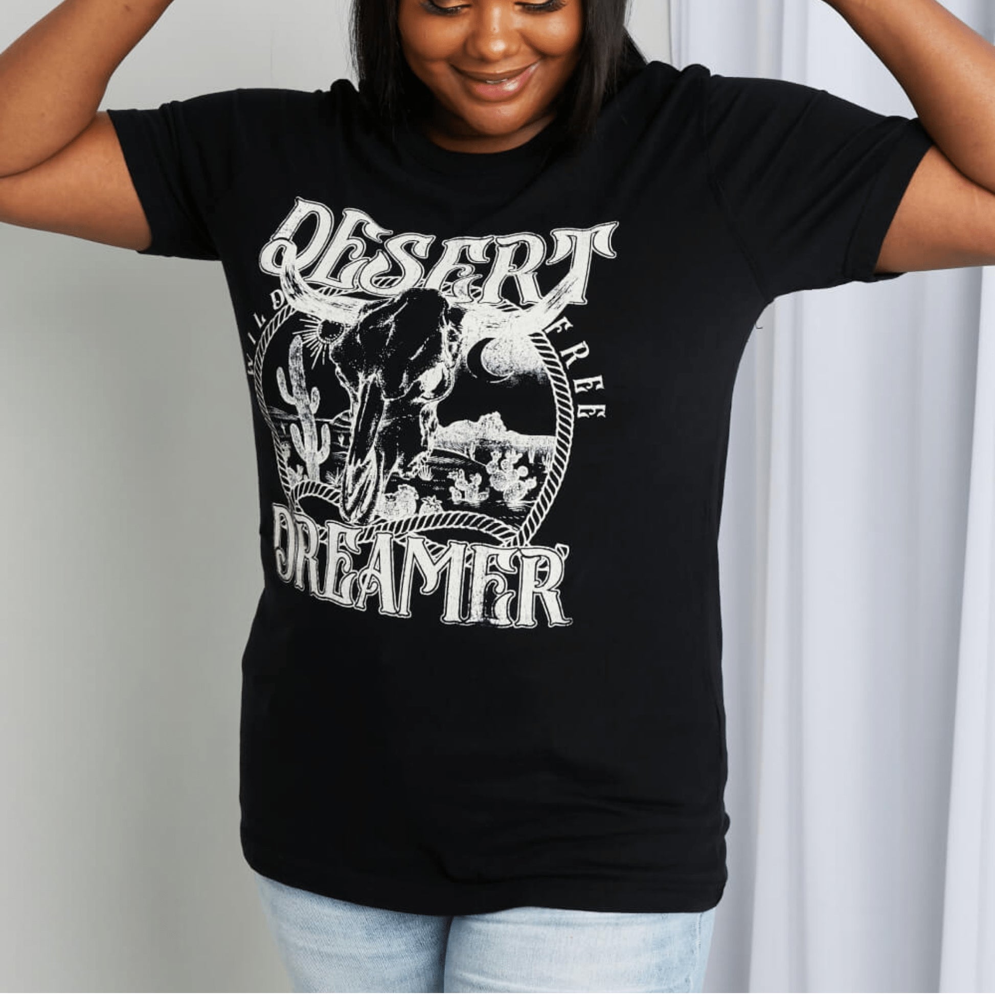 Lifestyle styling example of the black Desert Dreamer tee against a neutral background.