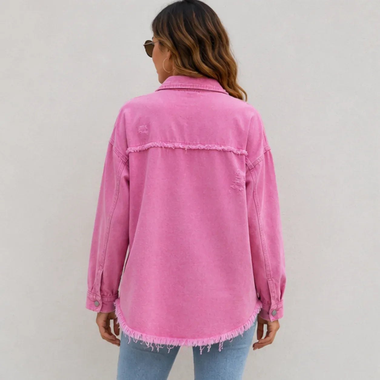 Back view of women's pink distressed denim shacket showing relaxed fit and frayed hem