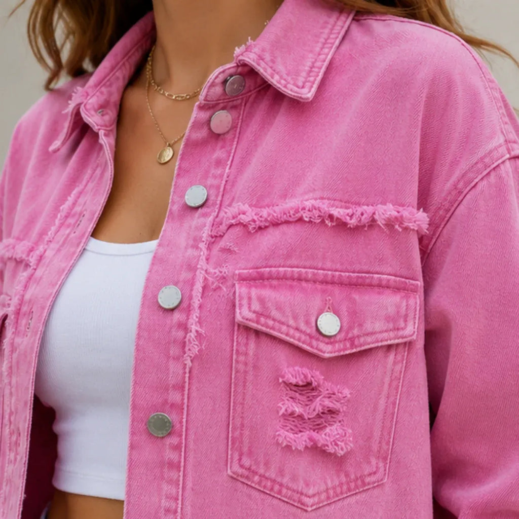 Close-up of pink distressed denim shacket showing flap pocket, buttons, and frayed detailing